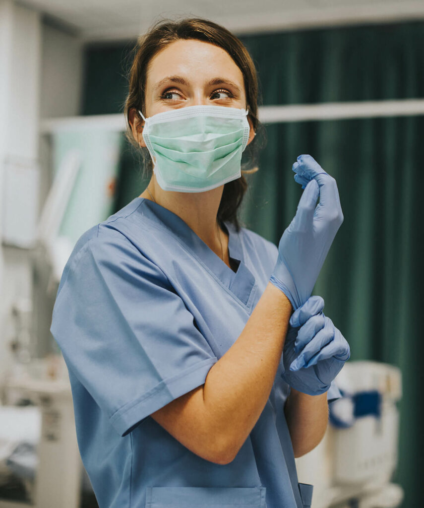 Une infirmière qui enfile des gants pour faire son travail