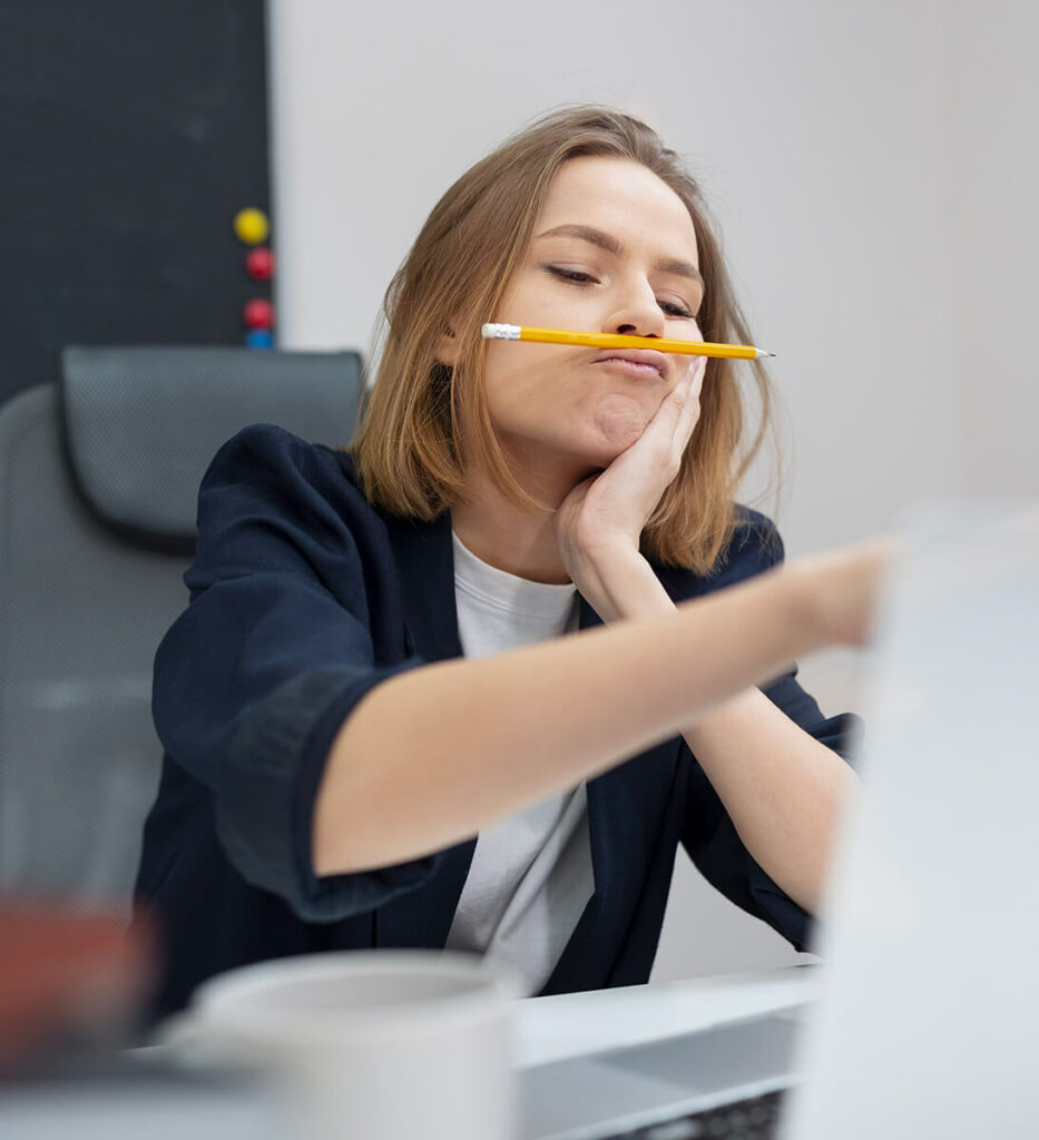 Une femme a posé un crayon de bois entre son nez et sa lèvre supérieure. Elle s'ennuie au travail et cherche à passer le temps.