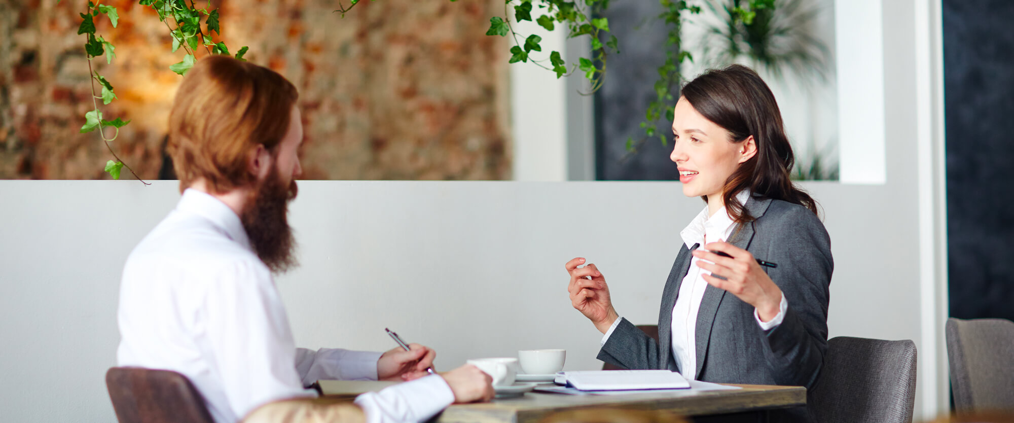 Une femme, consultante en bilan de compétences et un homme sont assis autour d'une table, ils parlent.