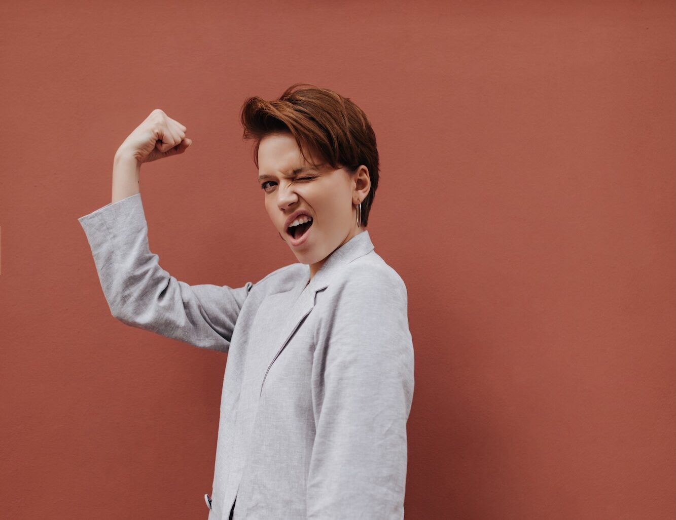 Jeune femme en costume gris clair qui contracte son bras droit en signe de force